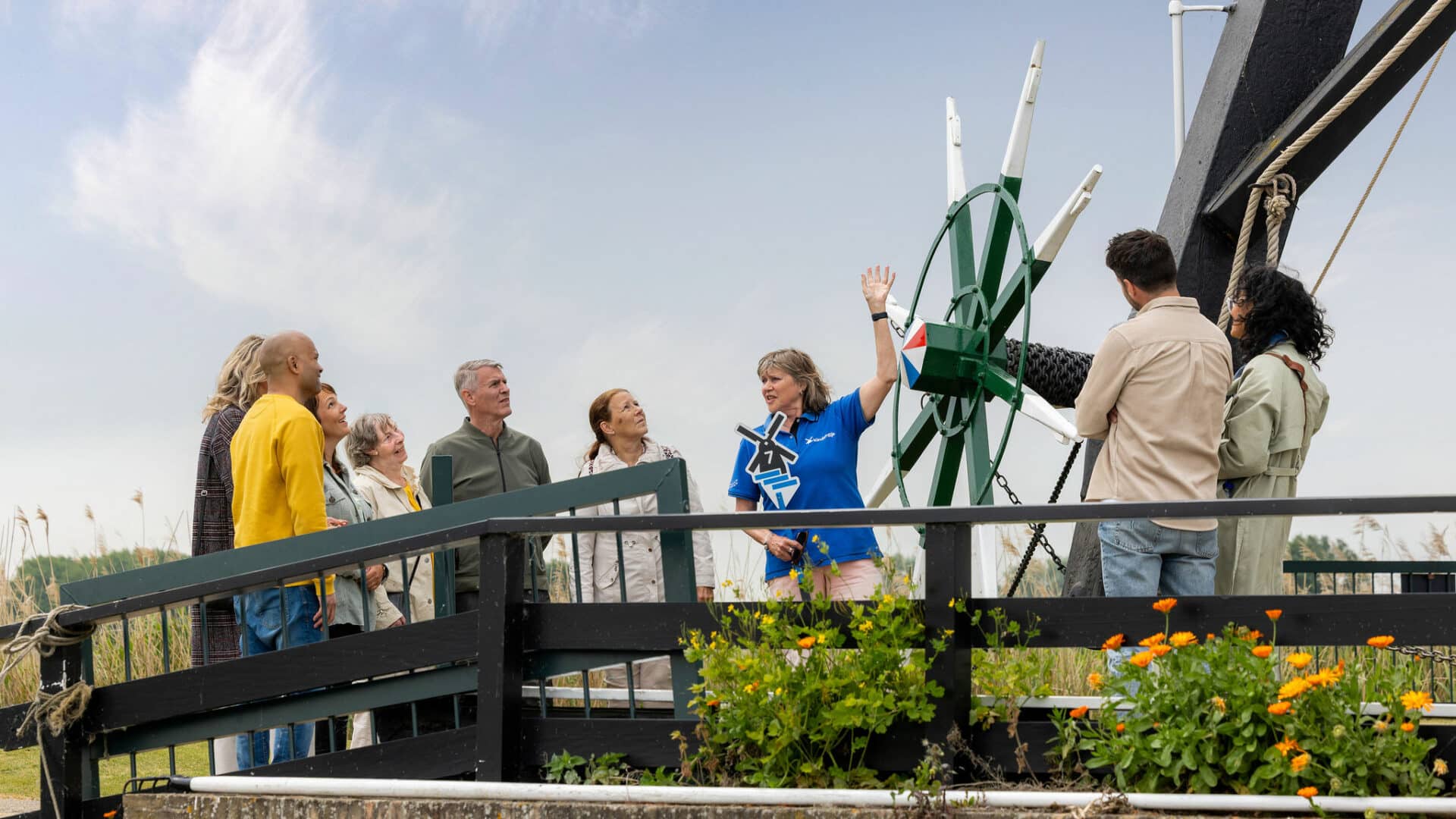 Gids in Kinderdijk-kleding heeft uitleg aan een groep bezoekers bij Museummolen Nederwaard in Kinderdijk