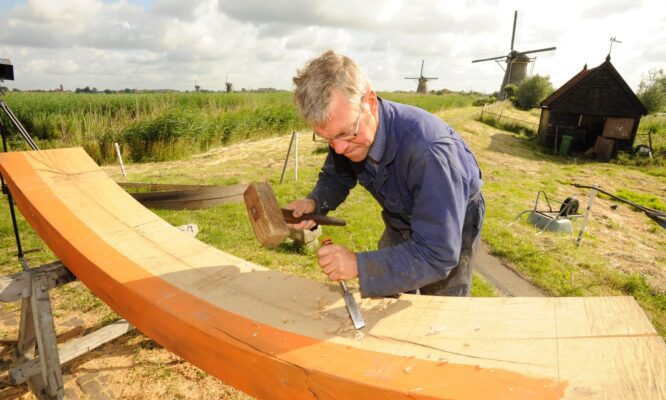 Molenmaken aan het werk in Werelderfgoed Kinderdijk met op de achtergrond molens