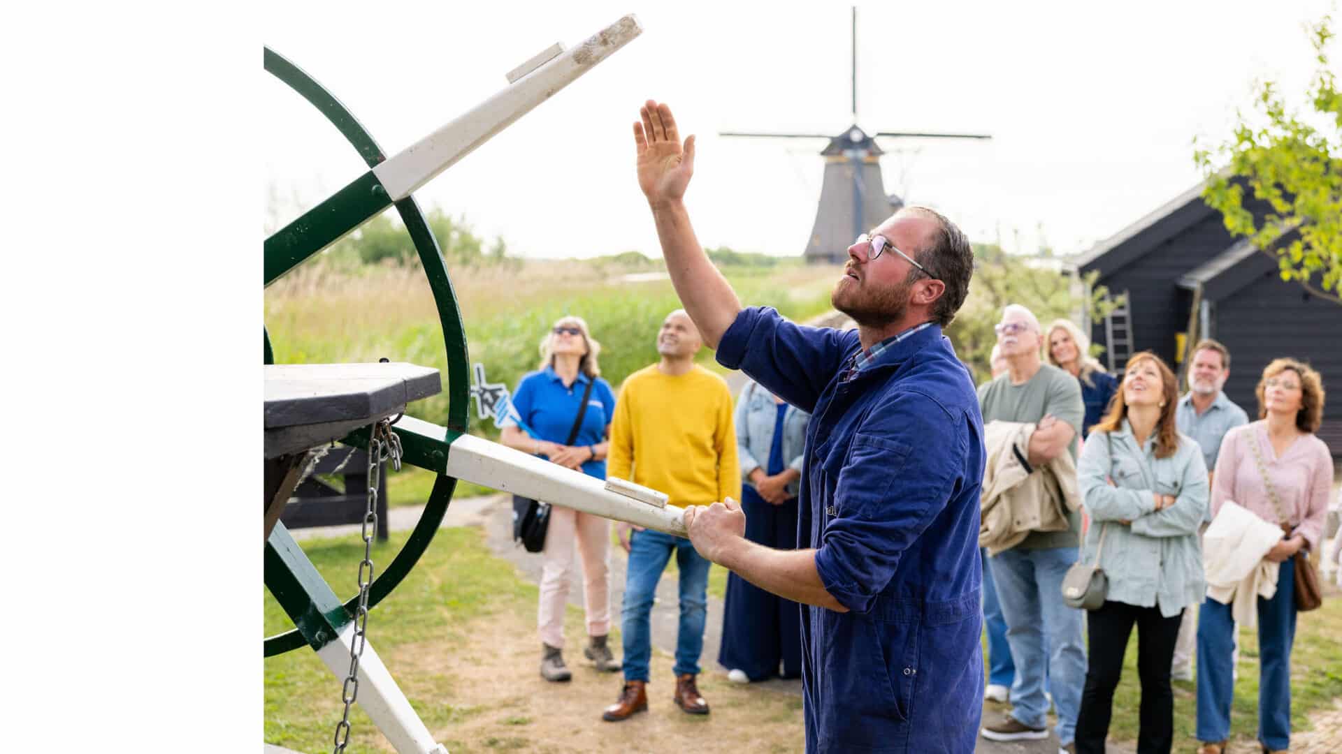 A miller is explaining things to a group in Kinderdijk while standing next to the mill’s winding wheel.