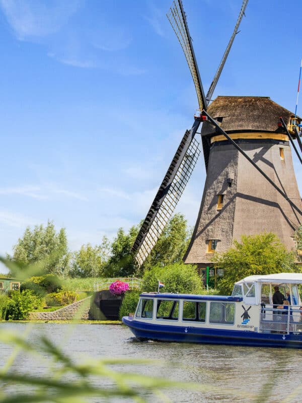 Rondvaartboot Hopper vaart met bezoekers langs een molen in Kinderdijk.