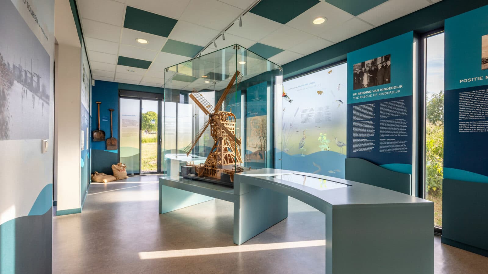 Een kijkje in de expositie in Hulpgemaal de Fabriek in Kinderdijk. Middenin staat een vrij grote modelmolen van hout in een vitrine.