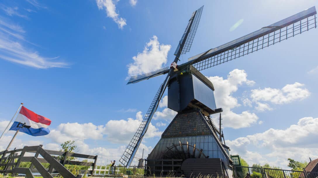 Museummolen Blokweer in Kinderdijk op een zomerse dag met link de Nederlandse vlag die wappert