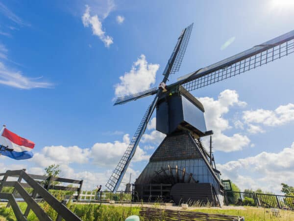 Museummolen Blokweer in Kinderdijk op een zomerse dag met link de Nederlandse vlag die wappert