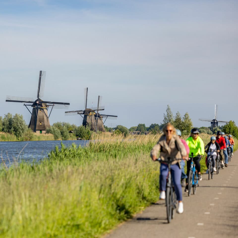 Fietsers fietsen over de Middelkade dwars door het gebied van UNESCO Werelderfgoed Kinderdijk