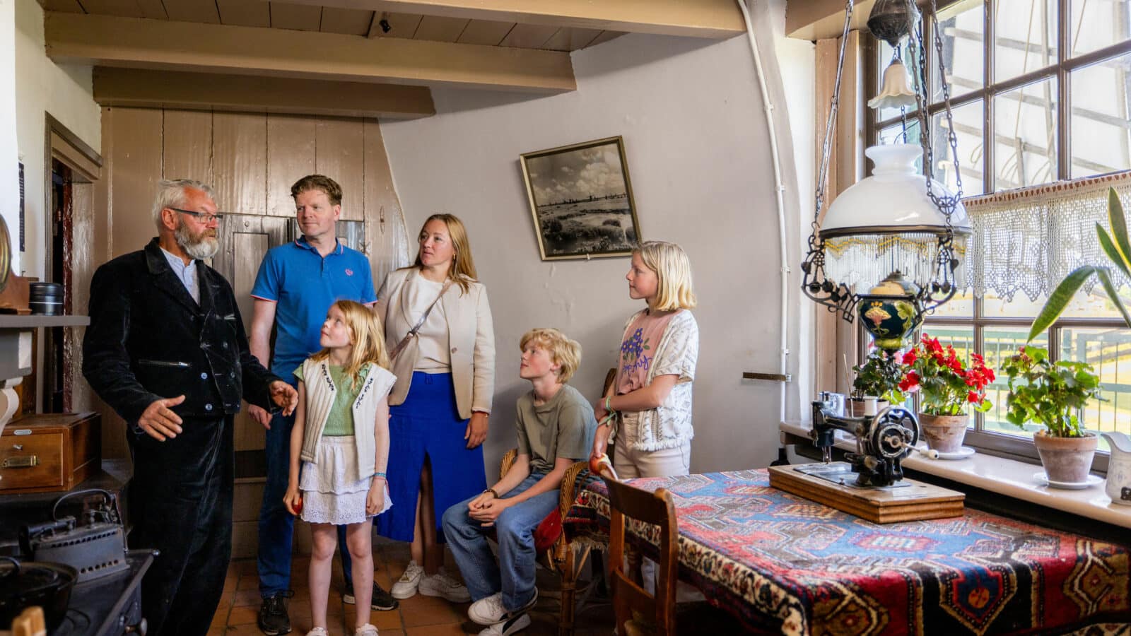 Een molenaar geeft een jong gezin uitleg in de woonkamer van Museummolen Nederwaard in Kinderdijk