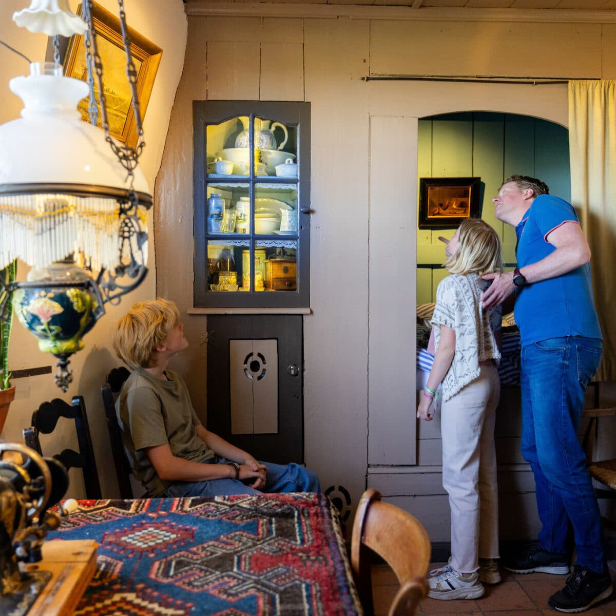 Vader met kinderen kijkt rond in de woonkamer van Museummolen Nederwaard in Kinderdijk.
