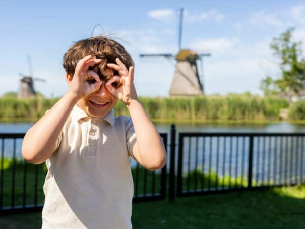 Kind maakt een grappig gezicht in Kinderdijk met op de achtergrond een molen.