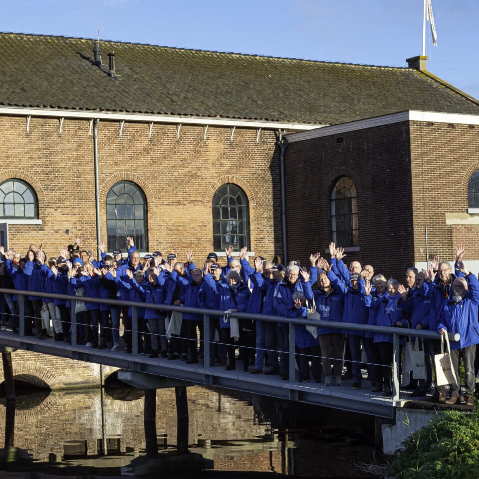 Medewerkers en vrijwilligers van Kinderdijk opgesteld op de brug richting het Wisboomgemaal.