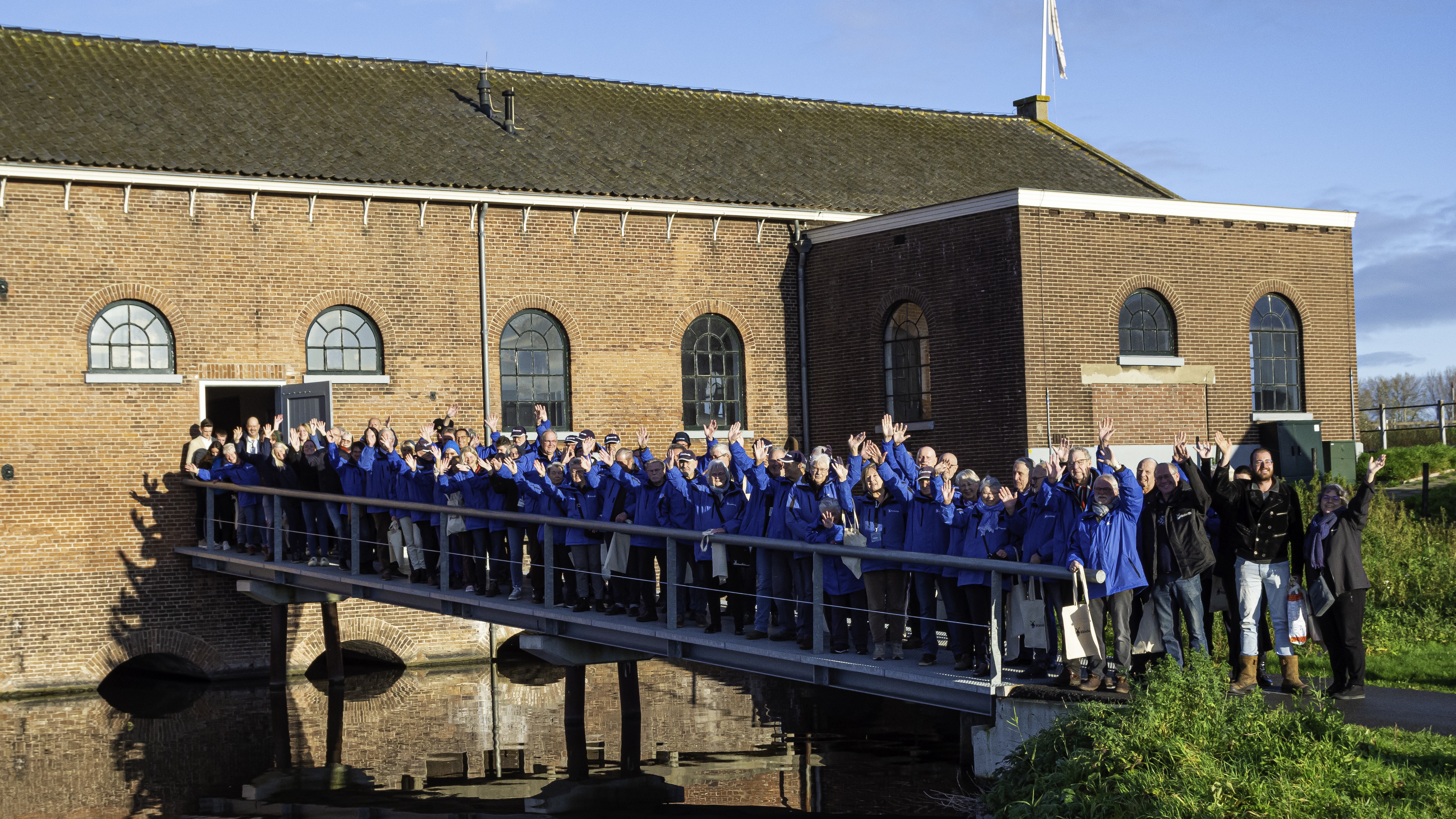 Medewerkers en vrijwilligers van Kinderdijk opgesteld op de brug richting het Wisboomgemaal.