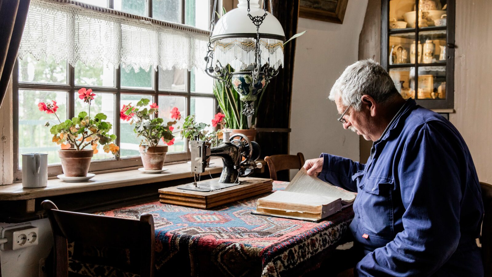 Een molenaar leest in de woonkamer van Museummolen Nederwaard een boek.