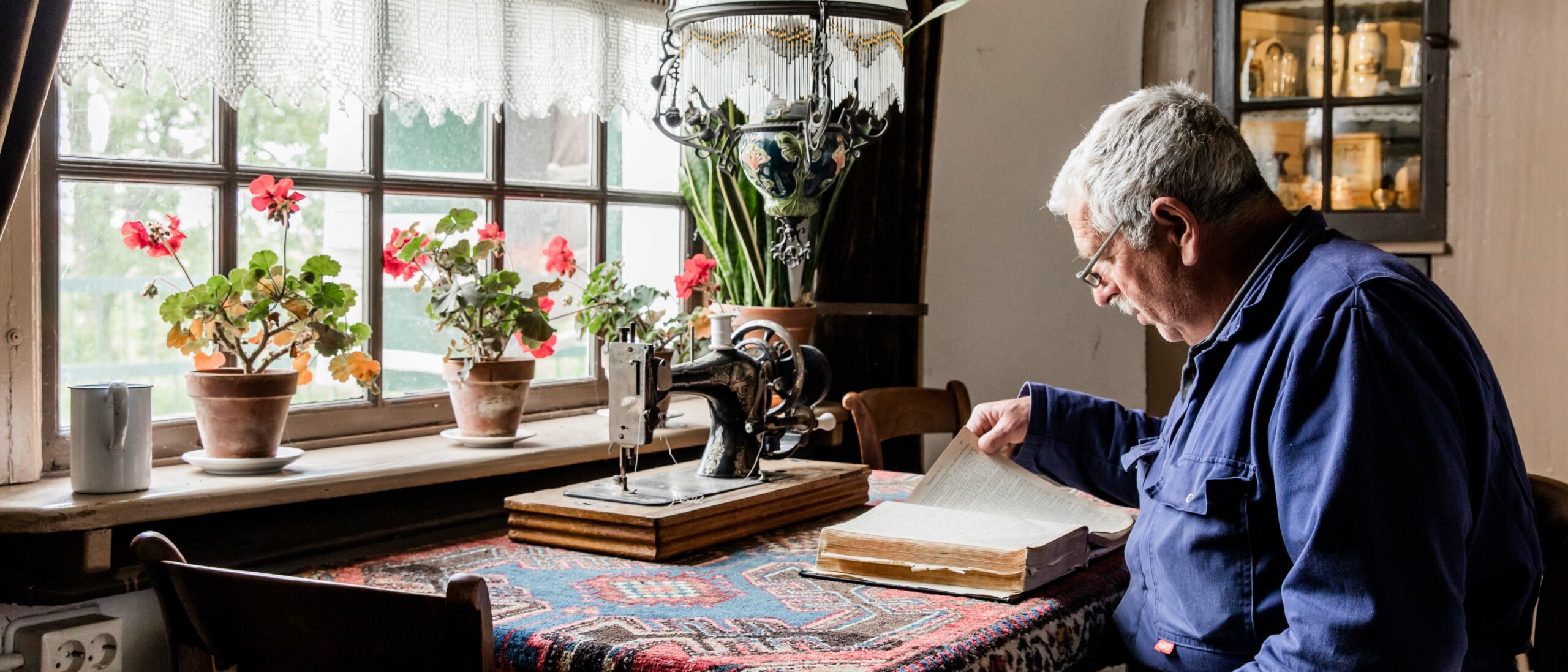 Een molenaar leest in de woonkamer van Museummolen Nederwaard een boek.