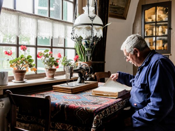 Een molenaar leest in de woonkamer van Museummolen Nederwaard een boek.