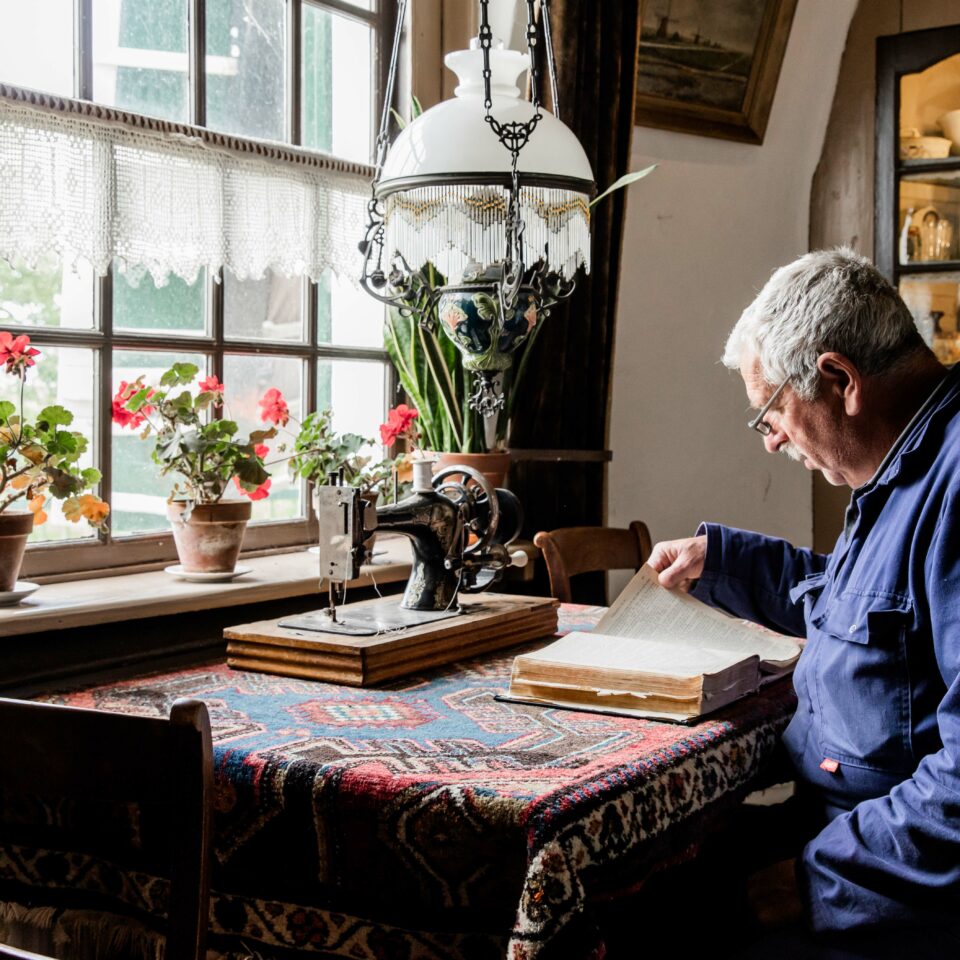 Een molenaar leest in de woonkamer van Museummolen Nederwaard een boek.