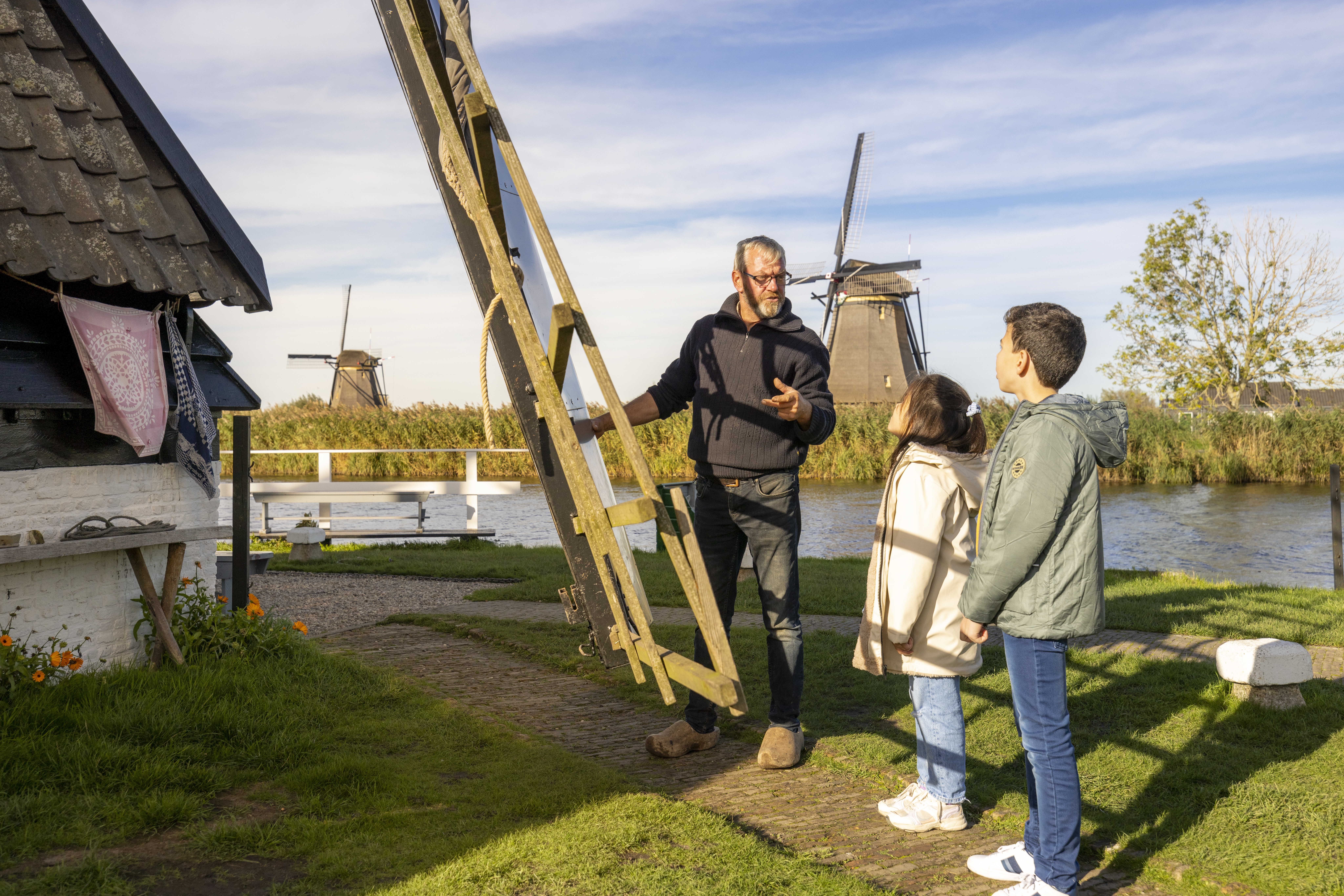 Molenaar geeft uitleg bij Museummolen Blokweer aan twee nieuwsgierige kinderen.
