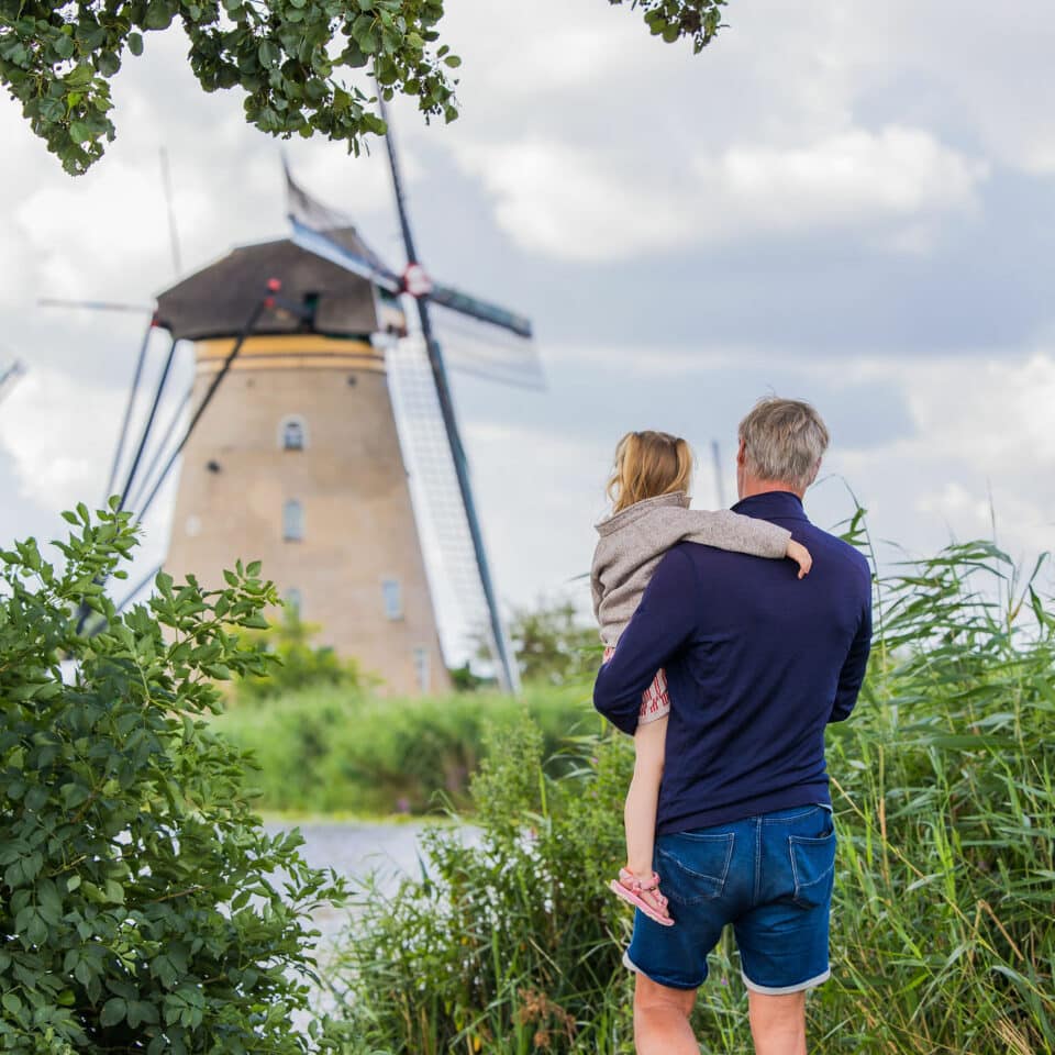 (Groot)ouder met kind kijkt uit over een molen van de Nederwaard in Kinderdijk