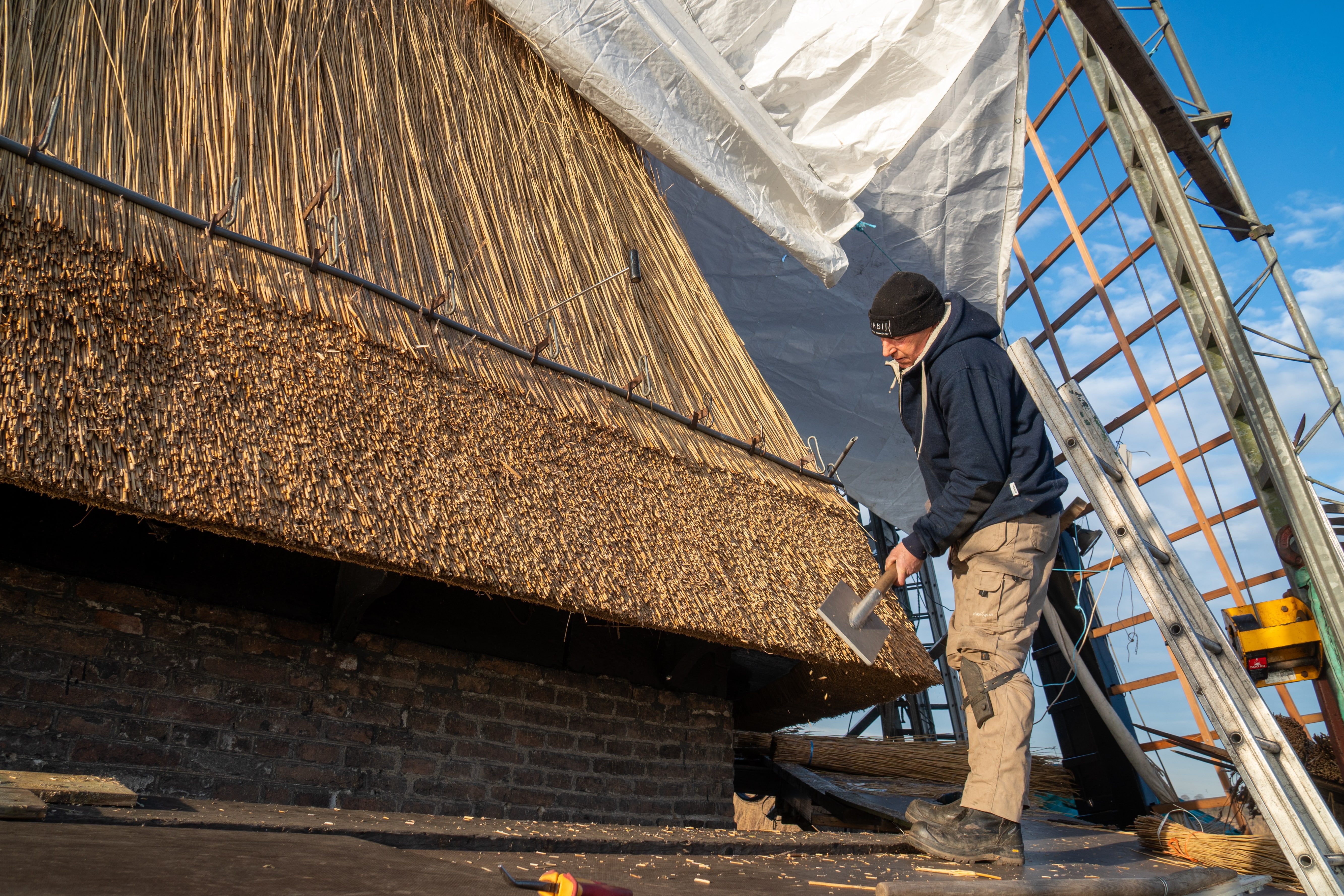 Een riet dekker aan het werk aan een molen in Kinderdijk voor het plaatsen van nieuw riet.