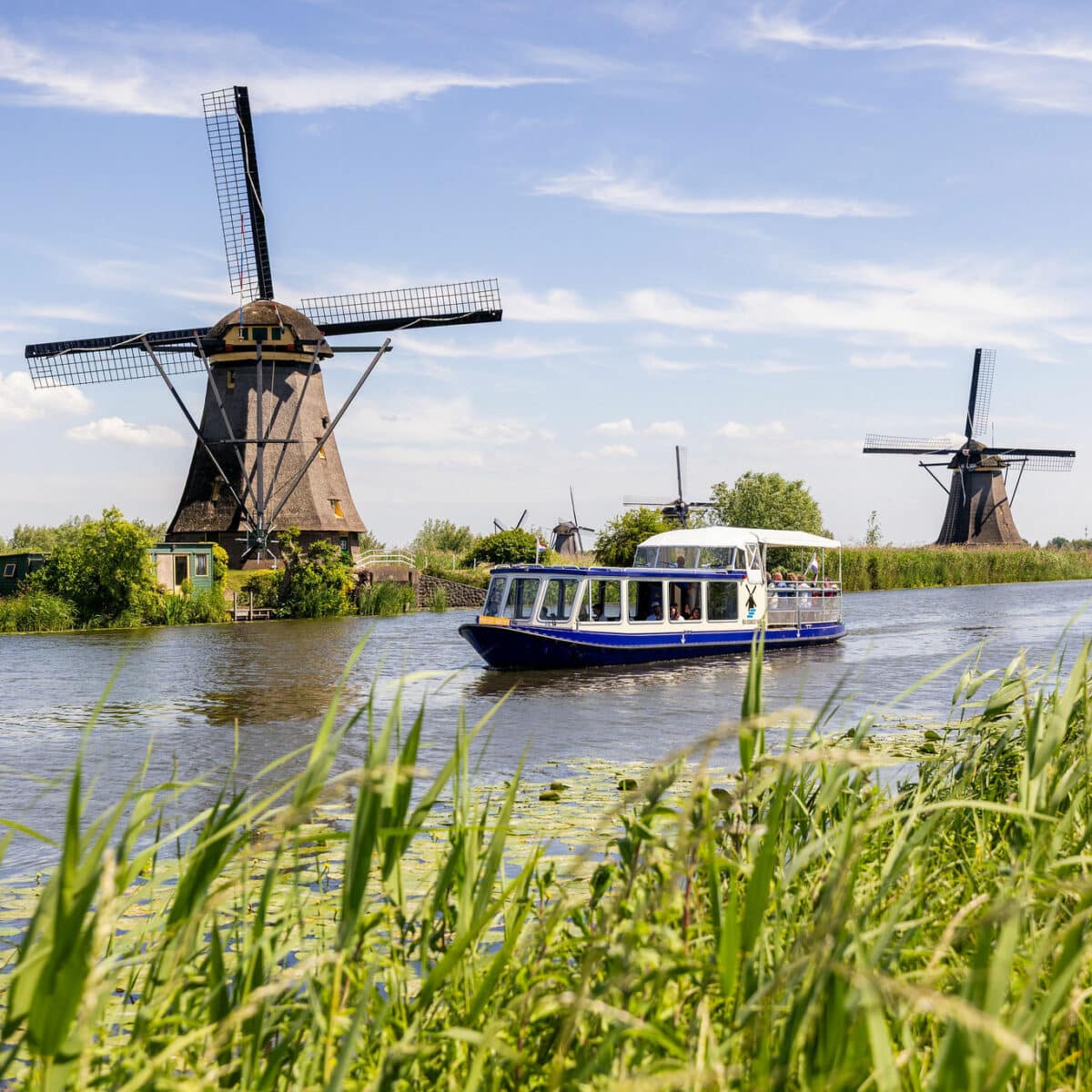 De rondvaartboot Hopper in Kinderdijk langs de molens op een zomerse dag.