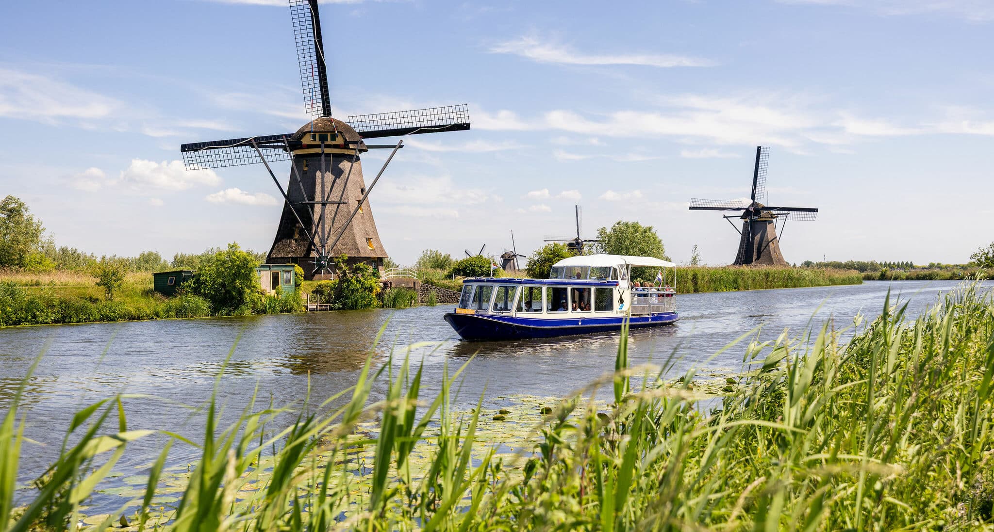 The Hopper sightseeing boat in Kinderdijk sailing past the windmills on a summer day.