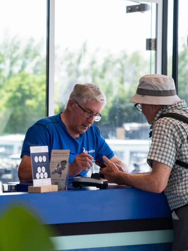 Vrijwilliger in Kinderdijk helpt een bezoeker aan tickets in het Bezoekerscentrum.