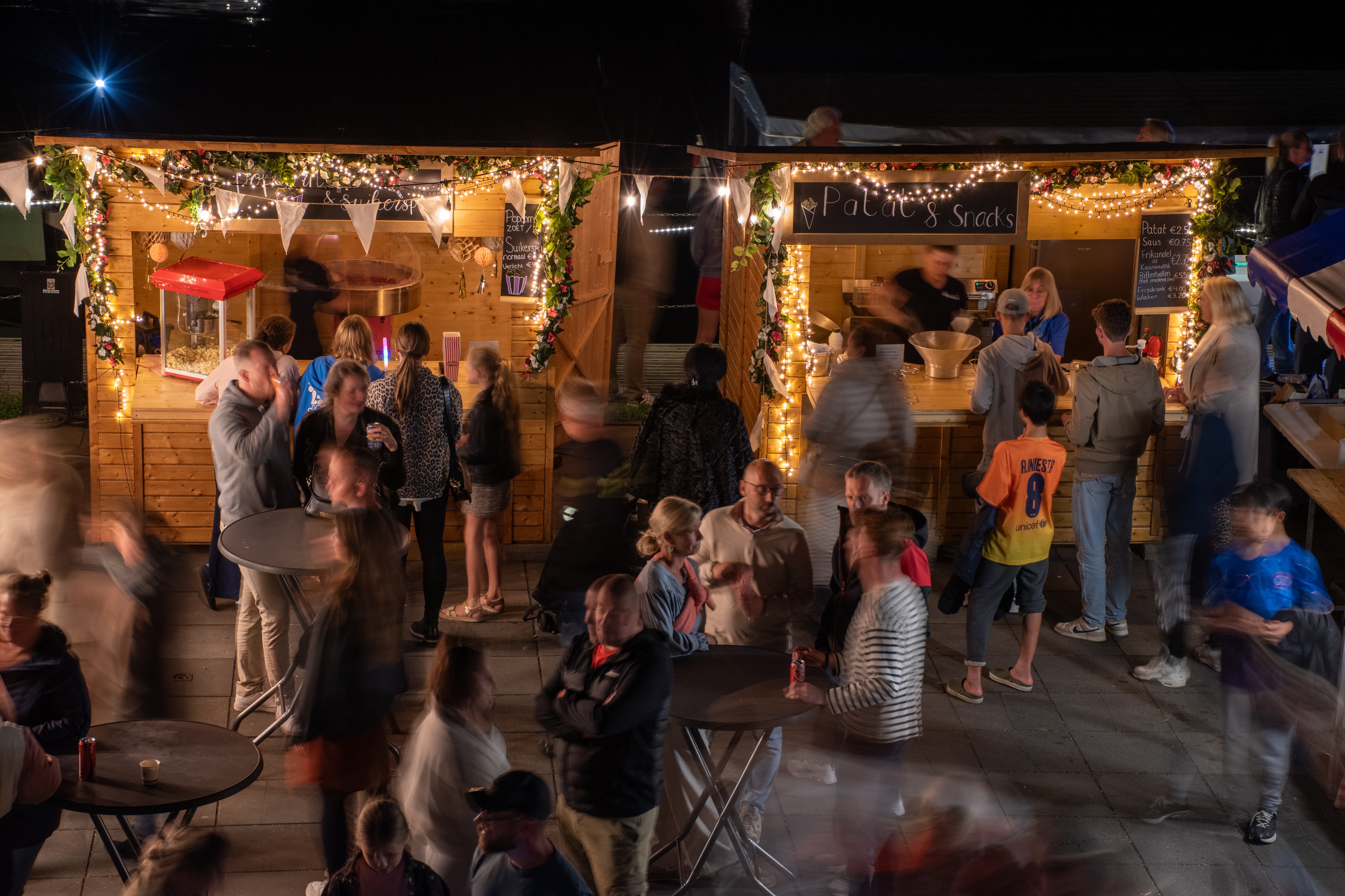 Mensen staan op een gezellig terras vlakbij het bezoekerscentrum van Kinderdijk tijdens de Verlichtingsweek 2025
