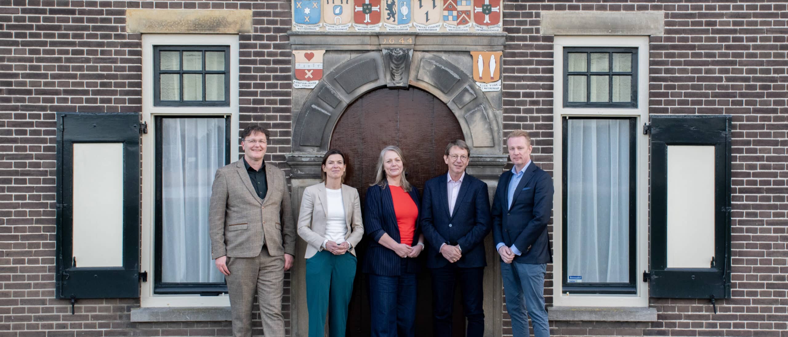 Groepsfoto van de leden van de Raad van Toezicht van Kinderdijk, voor het Waardhuis.