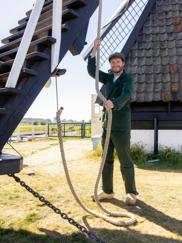 Een molenaar op klompen in Kinderdijk bij de vang (rem) van de molen.