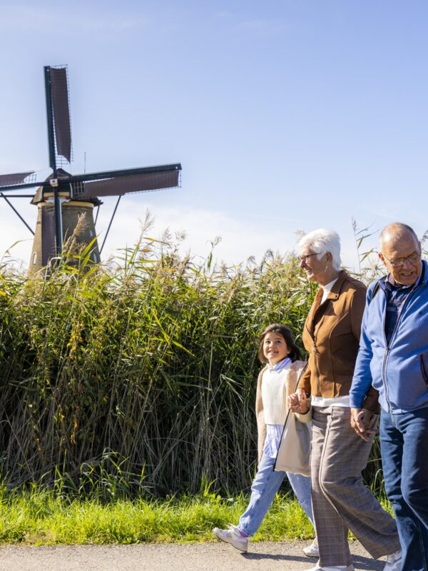 Familie loopt door het molengebied van UNESCO Werelderfgoed Kinderdijk
