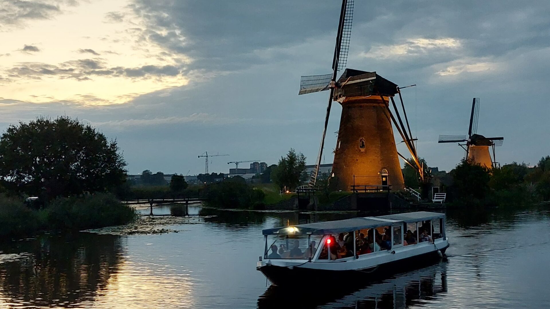 Borrelboot vaart langs de verlichte molens tijdens de Verlichtingsweek in Kinderdijk